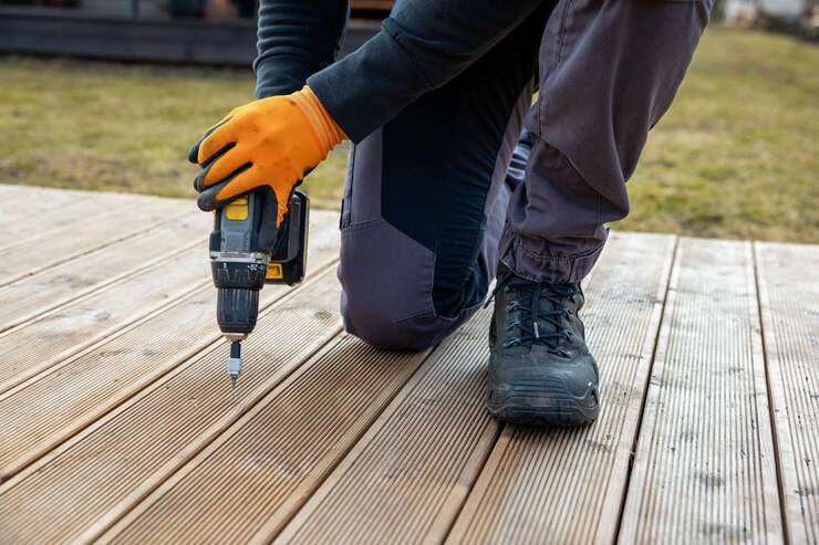 Deck terrace construction builder hand with electric screwdriver installing impregnated wooden boards 664057 2781