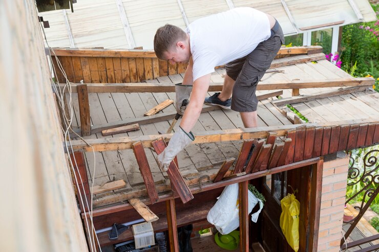 Man knocks old rotten wooden plank with hammer from parsing roof 308589 1102